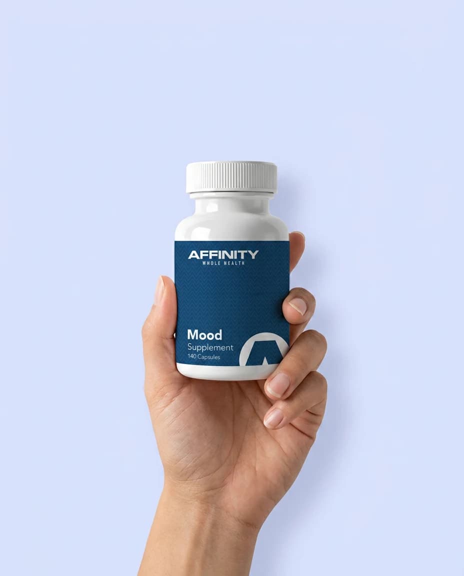 A hand holding an Affinity Mood supplement bottle