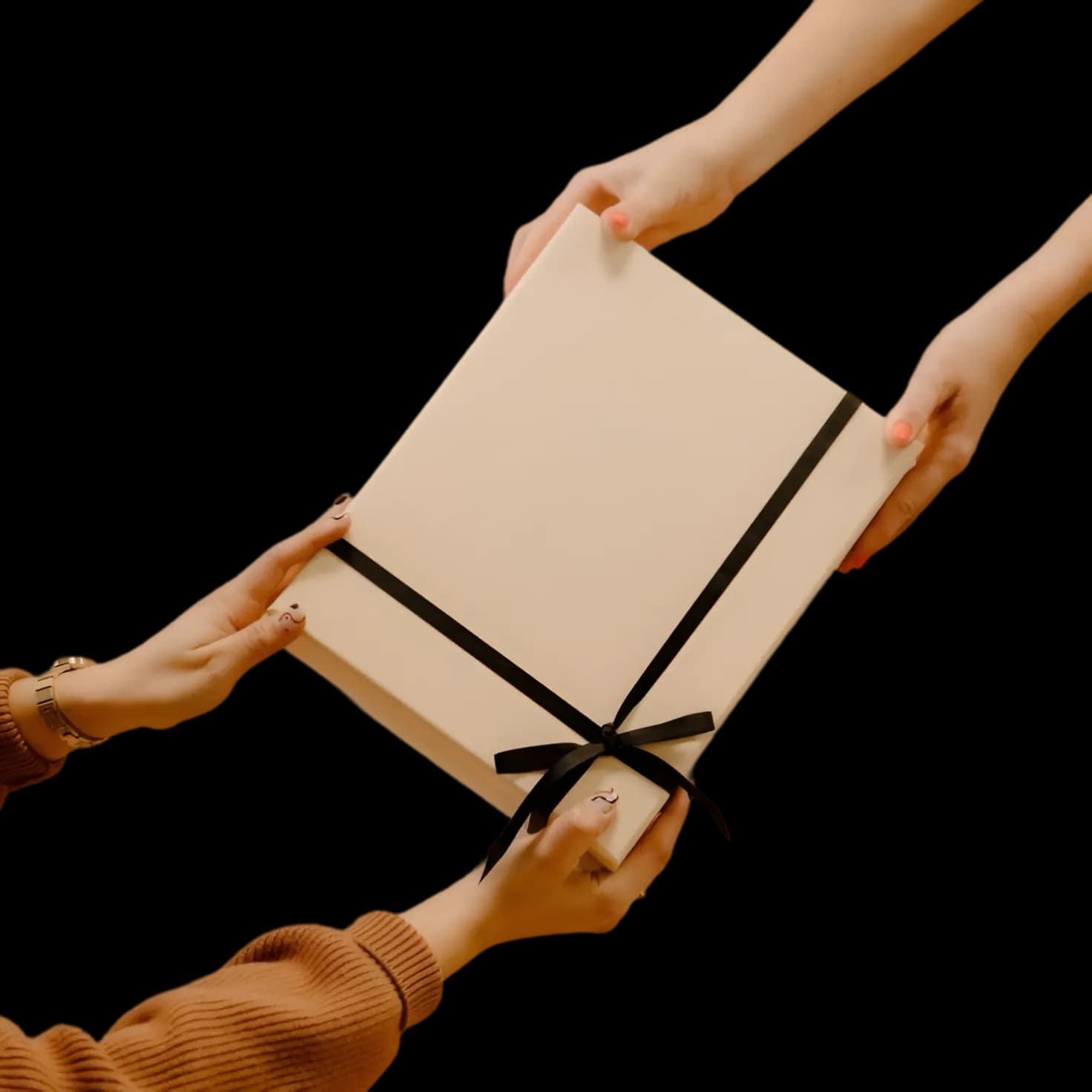 Two pairs of hands passing a plain box tied with a black ribbon
